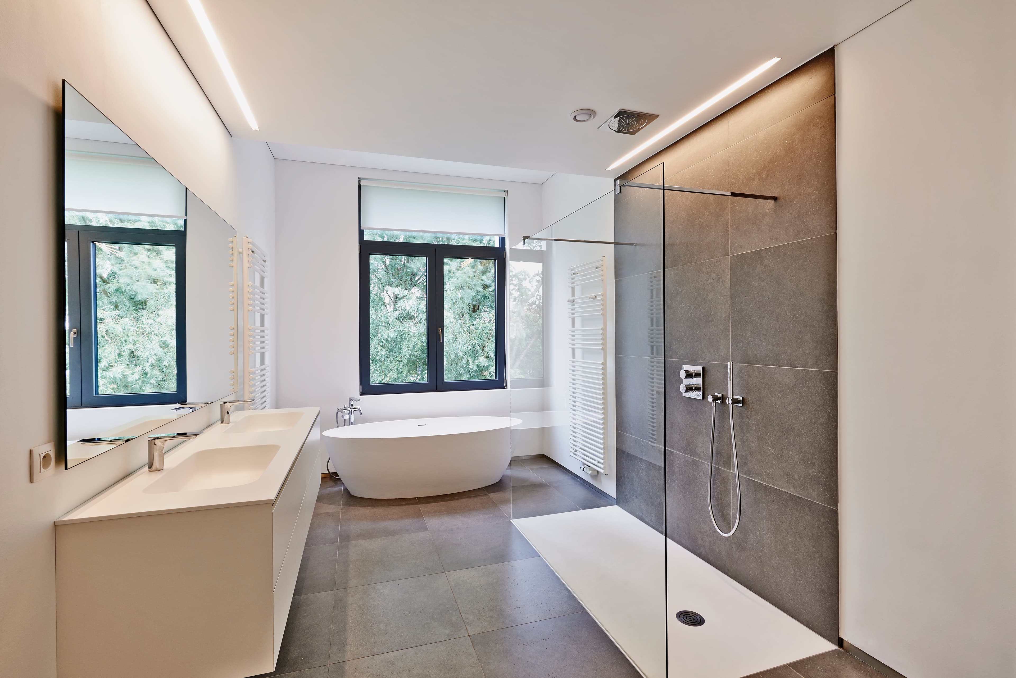 Modernisiertes Badezimmer in Frankfurt: bodenebene Dusche mit Natursteinfliesen, freistehende Badewanne und neue Sanitärinstallation